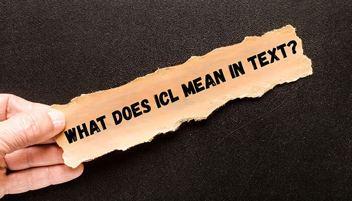 Torn paper with What does icl mean in text? held by a hand on black background.