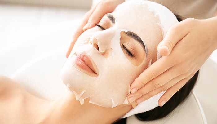 Relaxing facial treatment with a hydrating sheet mask, an essential step in the Korean Skincare Routine for radiant skin.