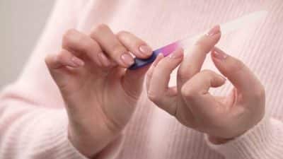 Woman filing her natural nails with a nail file, demonstrating how to shape nails step by step for smooth, salon-quality results at home.