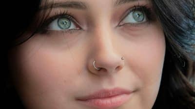 Close-up of a woman with captivating green eyes and dual nose piercings, reflecting modern style and individuality — showcasing Nose Piercing Meaning in contemporary fashion.