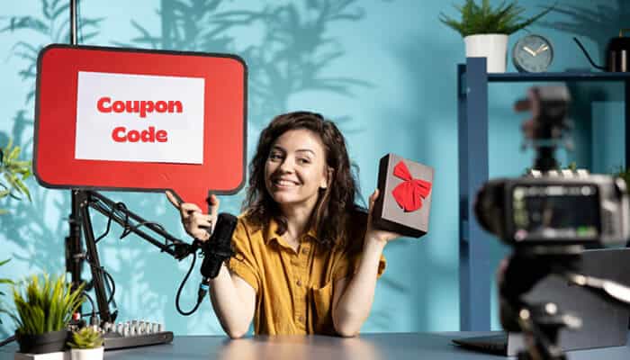 Person holding a gift box and a sign with the text 'Shein coupon code,' promoting Shein discount offers.