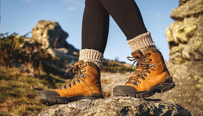 Top hiking boots picks - Fashion in beauty - Fashion in Beauty Best Boots For Men: A person hiking in durable tan boots, surrounded by rocky terrain, showcasing outdoor boots perfect for adventure and durability.