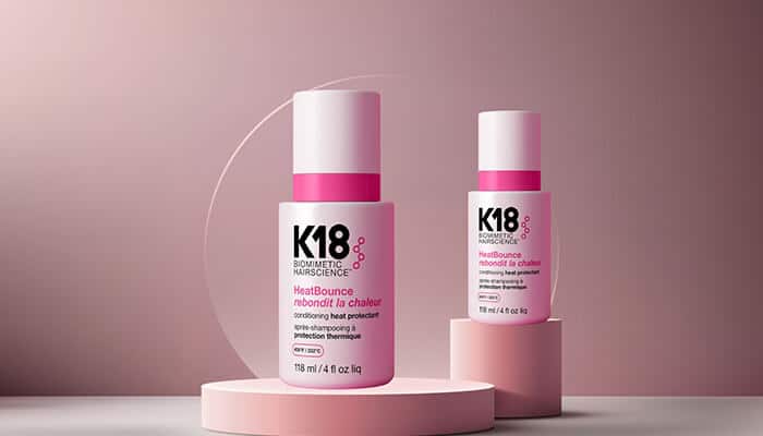 K18 HeatBounce Leave-In Conditioner Heat Protectant - Fashion in beauty - Fashion in Beauty K18 HeatBounce Leave-In Conditioner shown on a pink pedestal, highlighting advanced thermal protection technology as one of the Best Heat Protectant Spray options for preventing heat damage and improving hair strength.