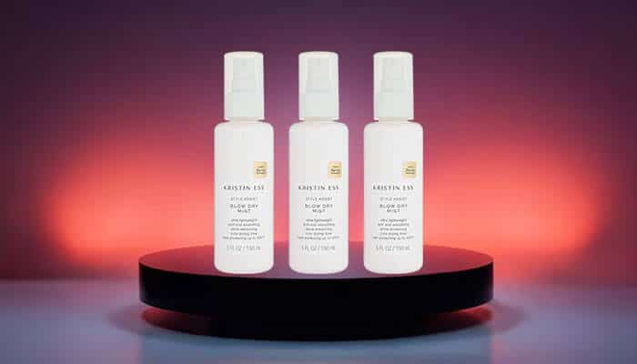 Kristin Ess Style Assist Blow Dry Mist Heat Protectant Spray - Fashion in Beauty - Fashion in Beauty Kristin Ess blow dry sprays displayed on a dark podium, providing lightweight heat defense and shine as a Best Heat Protectant Spray for salon-style results.
