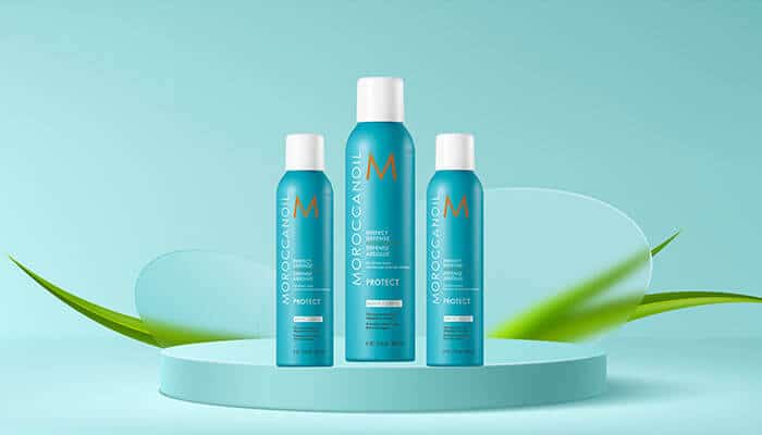 Moroccanoil Perfect Defense Heat Protectant - Fashion in Beauty - Fashion in Beauty Moroccanoil Protect sprays arranged on a minimal aqua podium, infused with argan oil to shield hair from heat, featured as a Best Heat Protectant Spray.