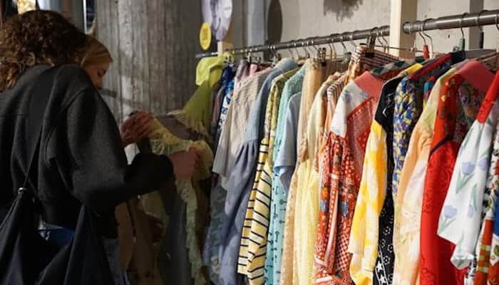 UK Sales Channels Compared - Fashion in beauty - Fashion in Beauty Two shoppers browse a clothing rack filled with colorful shirts in a shop.