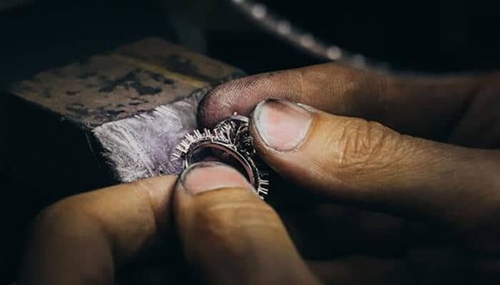 What Shapes Resale Value - Fashion in beauty - Fashion in Beauty Close-up of a jeweler's hands polishing a silver ring on a workbench with a textured edge.