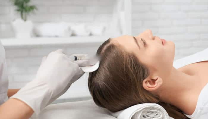 Comparing Laser Devices - Fashion In Beauty - Fashion in Beauty Hair Growth Technologies applied in a clinical scalp treatment session showing a woman receiving advanced dermatological therapy using a specialized handheld device on the scalp, representing modern non-invasive methods like low-level laser therapy and follicle stimulation designed to support natural hair regeneration and improve hair density.