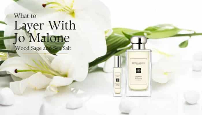 Jo Malone Wood Sage and Sea Salt - Fashion In Beauty - Fashion in Beauty Jo Malone Wood Sage and Sea Salt perfume bottles beside white lilies, illustrating fragrance layering ideas for creating a fresher, more personalized scent.