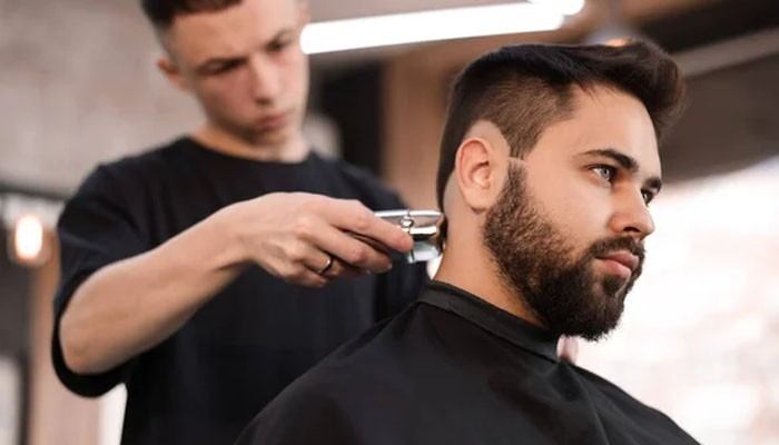 Explain Your Daily Routine - FashionIn Beauty - Fashion in Beauty Taper Fade Textured Fringe haircut being shaped by a professional barber, featuring clean tapered sides, blended fade details, and a textured top style for a modern men’s grooming look