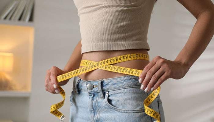 How to Measure Yourself for Size 28 Jeans - Fashion In Beauty - Fashion in Beauty What Size Is 28 in Womens Jeans guide showing a woman measuring her waist with a tape measure to find the correct denim fit and size.