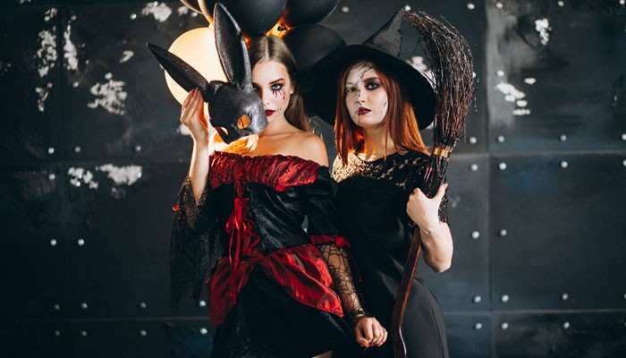 Best Halloween Costumes for Adults - Fashion In Beauty - Fashion in Beauty Halloween Costumes for adults featuring a gothic witch in a pointed hat and a masquerade-inspired woman holding a black rabbit mask.